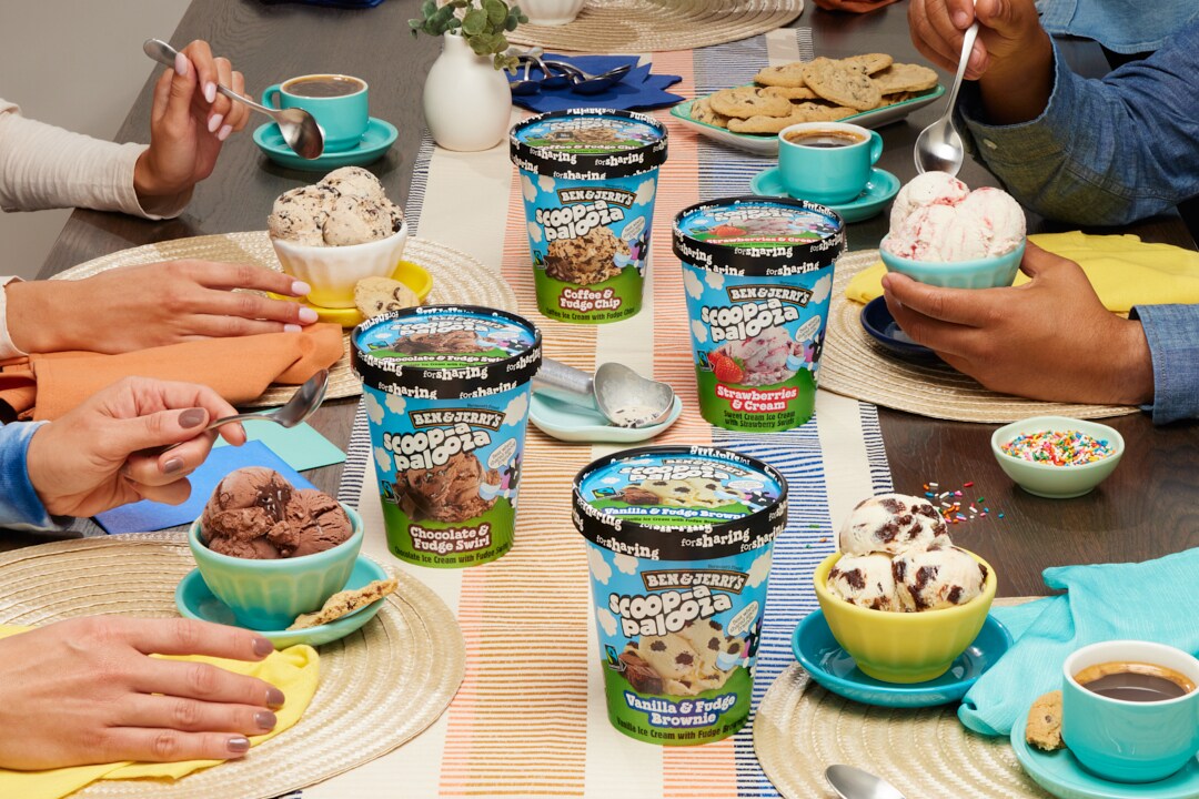 People at a table with containers of Ben & Jerry's Scoop-apalooza ice cream.