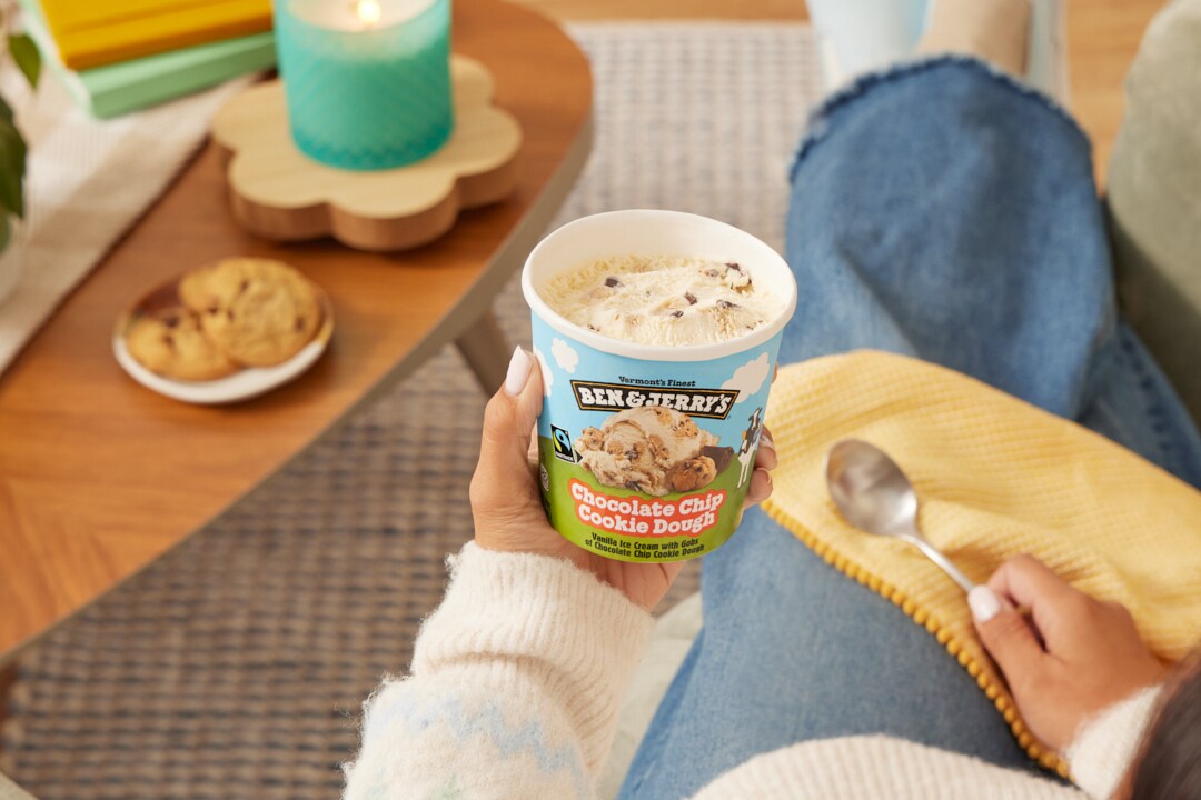 Hand adds sprinkles on top of a bowl of Ben & Jerry's Chocolate Chip Cookie Dough Non-Dairy. Pint is nearby.