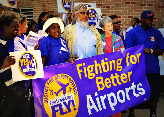 people holding Justice for Airport Workers sign