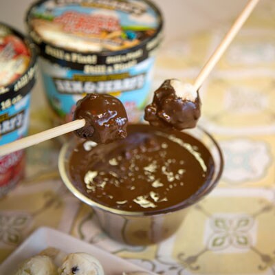 Ice cream balls being dipped into chocolate fondue.