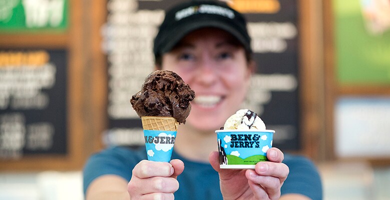 Scoop Shop employee holding a cone and a cup