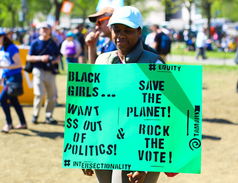 someone holding sign that says Black girls want $$ out of politics