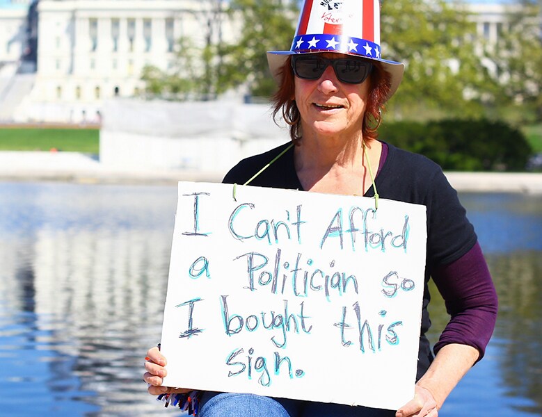 someone holding sign that says I can't afford a politician so I bought this sign