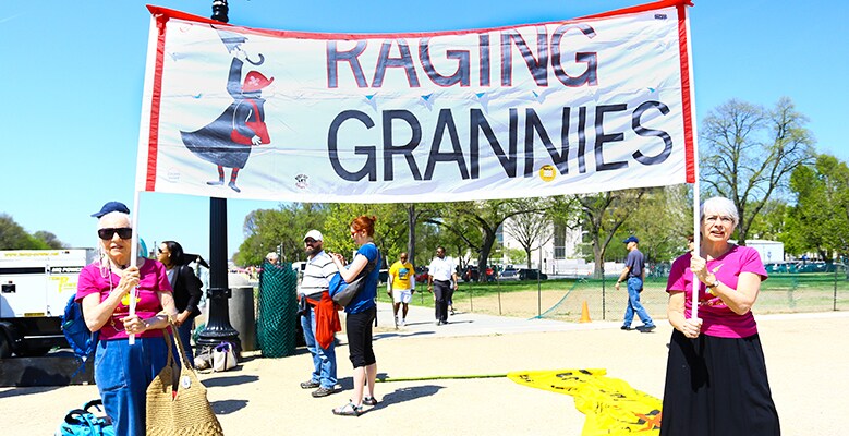 two people holding signs that says Raging Grannies