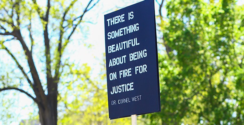 sign that says "There is something beautiful about being on fire for justice - Dr Cornel West