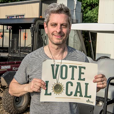 Man holding a vote local sign