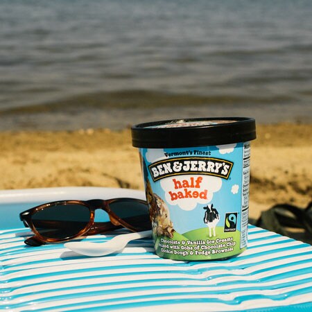 A Pint of Ben & Jerry's Half Baked sitting on a beach towel with sunglasses