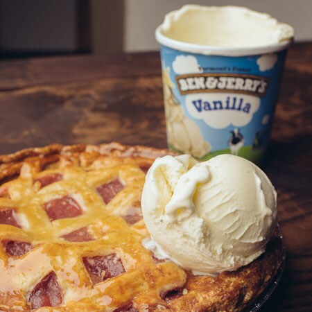 A Pint of Ben & Jerry's Vanilla with a scoop on top a freshly baked pie