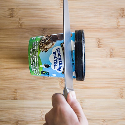 Ben & Jerry's Pint on its side with a knife cutting a slice of it