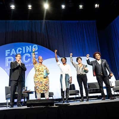 Four presenters stand onstage at the Facing Race conference, November 2018