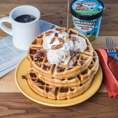 A plate of waffles with scoops of ice cream on top.