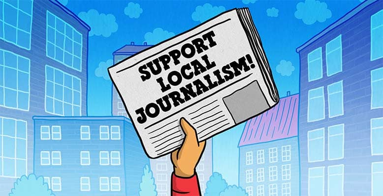 Hand holding a newspaper that says Support Local Journalism