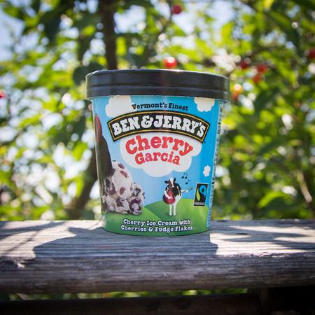A pint of Ben & Jerry's Cherry Garcia Ice cream sitting on a fence rail