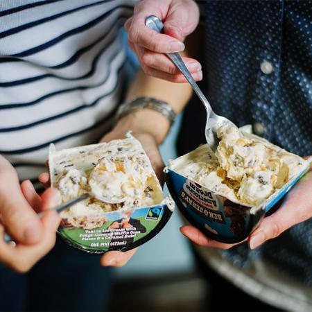 A pint of Ben & Jerry's Americone Dream cut in half being eaten
