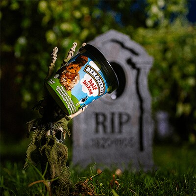 Half Baked being held by a skeleton hand in a grave yard