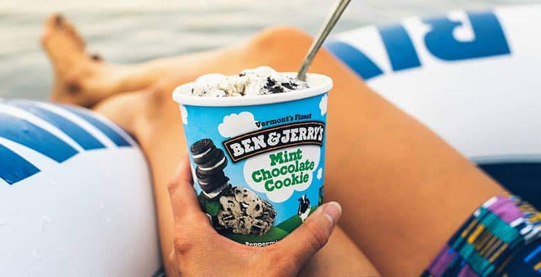 Person holding a pint of Mint Chocolate Cookie ice cream while floating on an inflatable tube